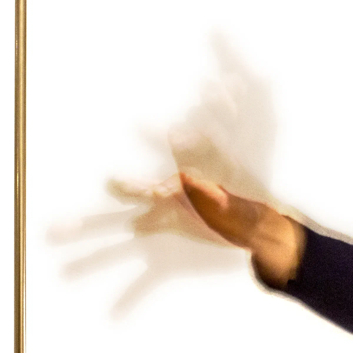 A hand moves horizontally near the theremin's vertical pitch antenna